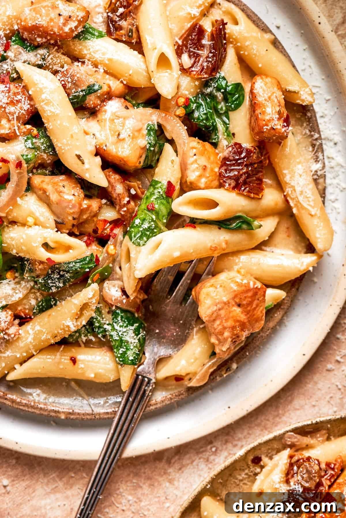 A fork rests in a plate of marry me chicken pasta.