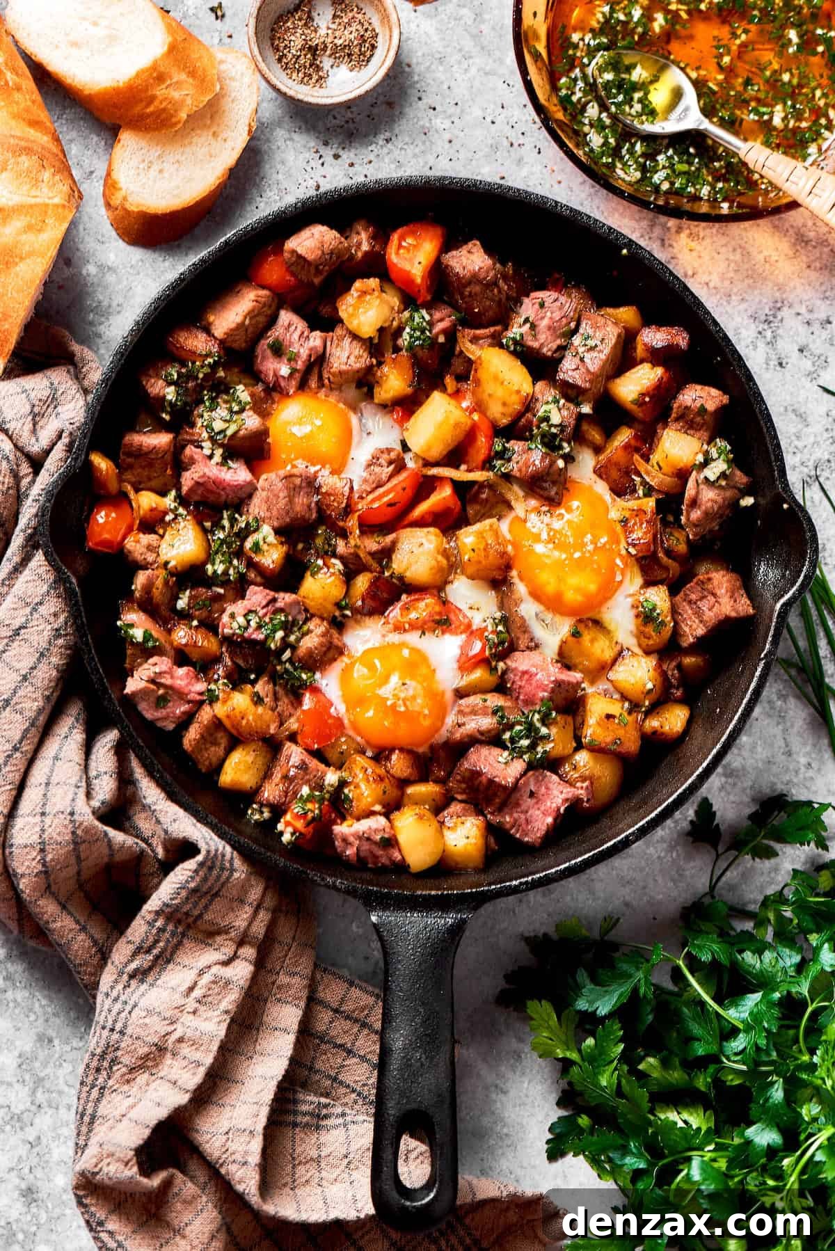 A sizzling skillet of perfectly cooked steak and eggs, with golden-brown potatoes and bright cherry tomatoes, topped with sunny-side-up eggs.