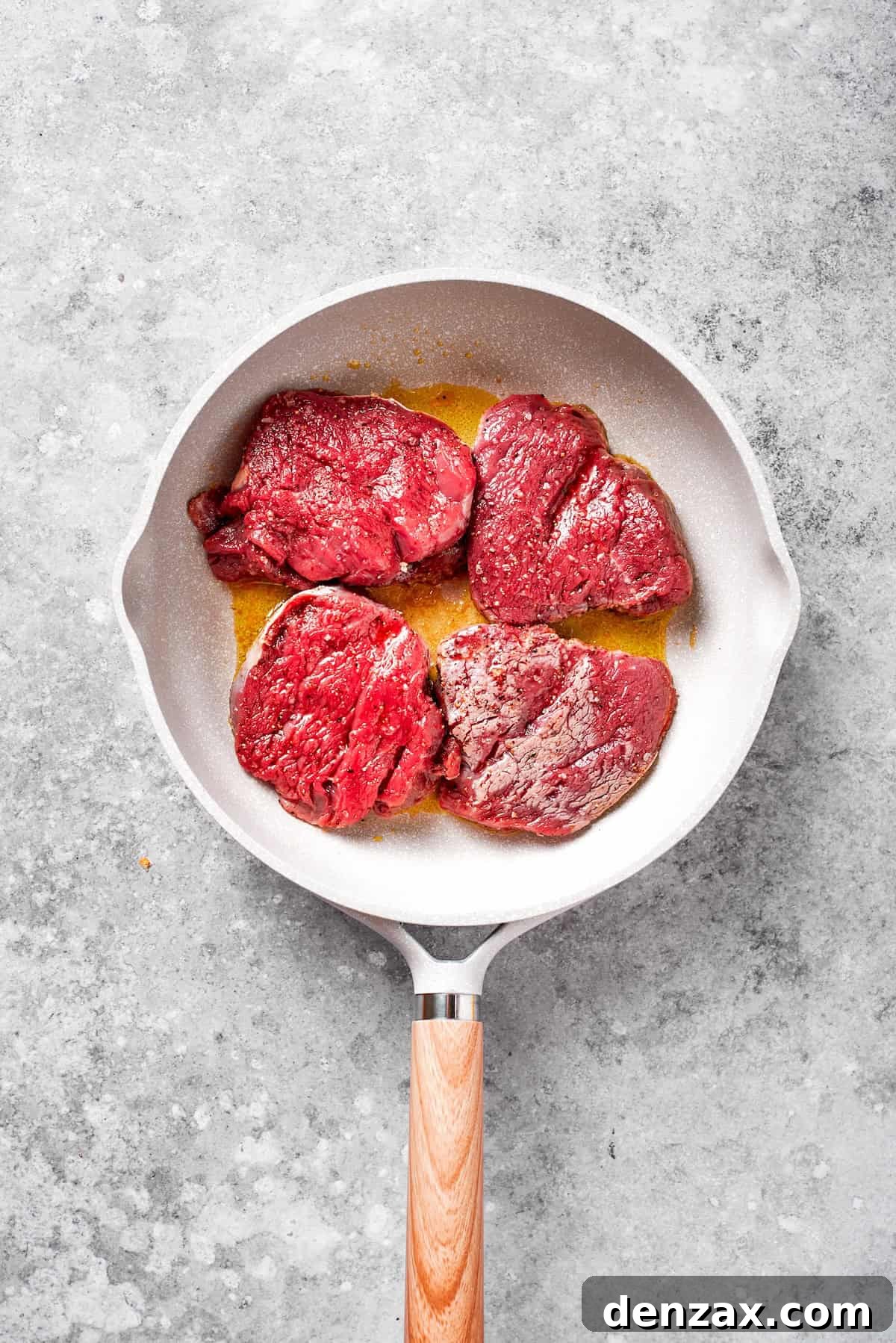 Four pieces of seasoned top sirloin steak searing beautifully in a hot skillet, developing a delicious crust.