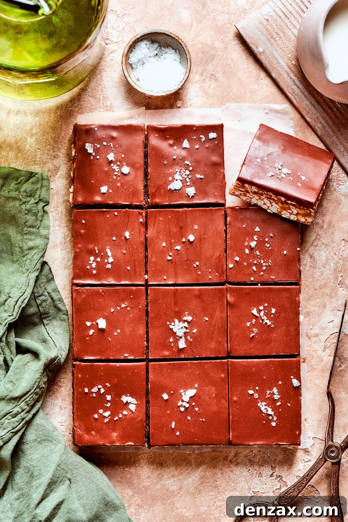 Flaky sea salt being sprinkled over a tray of a dozen scotcharoos.