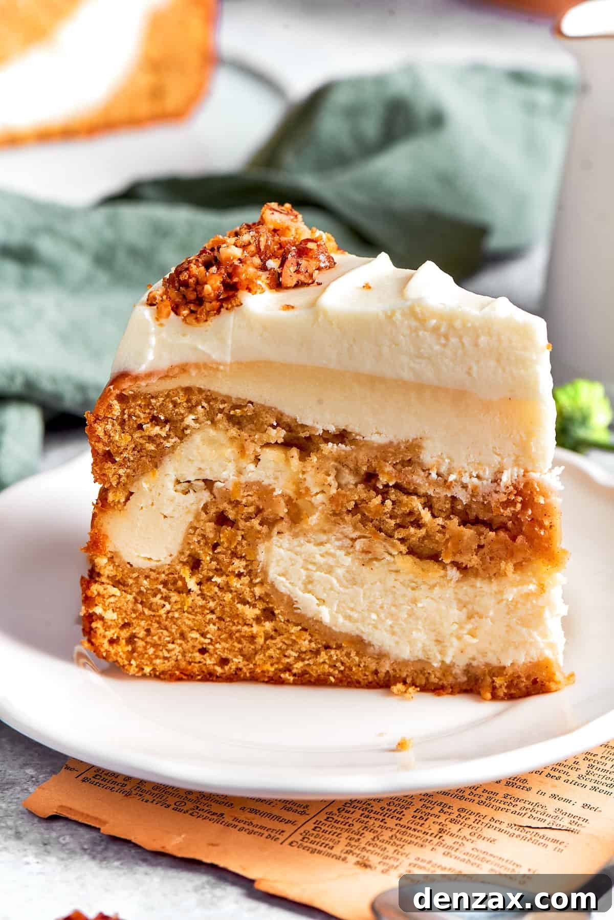 A thick slice of carrot cake cheesecake on a plate, showing distinct layers of carrot cake and cheesecake.