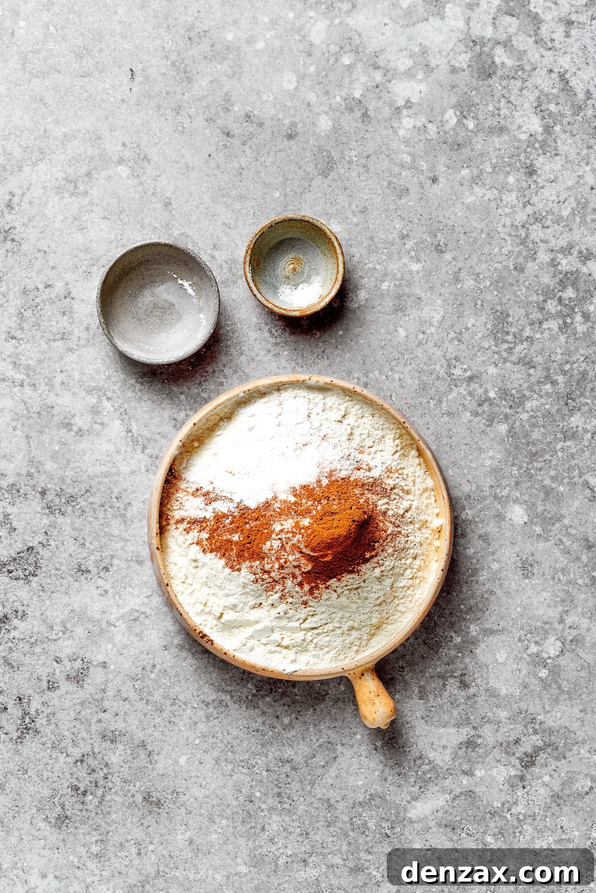 A bowl containing the dry ingredients for the carrot cake: flour, baking powder, salt, cinnamon, nutmeg, and ginger.