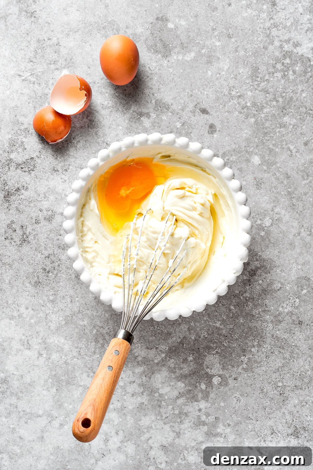 Cream cheese, sugar, and flour being whisked together in a bowl until smooth.