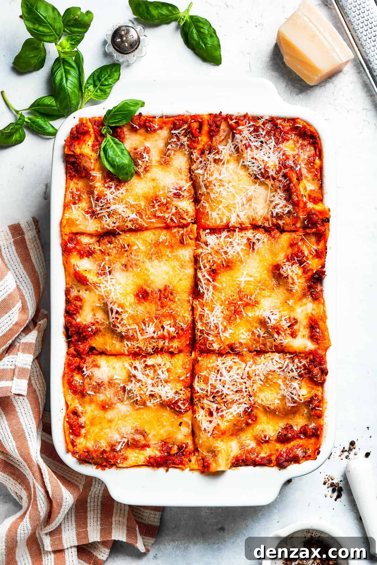 A pan of beef lasagna cut into squares, showing layers of pasta, meat sauce, and cheese.
