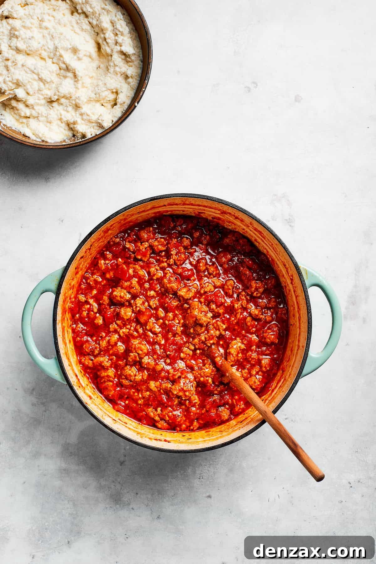 A rich, red beef tomato sauce simmering gently in a large pot, steam rising.