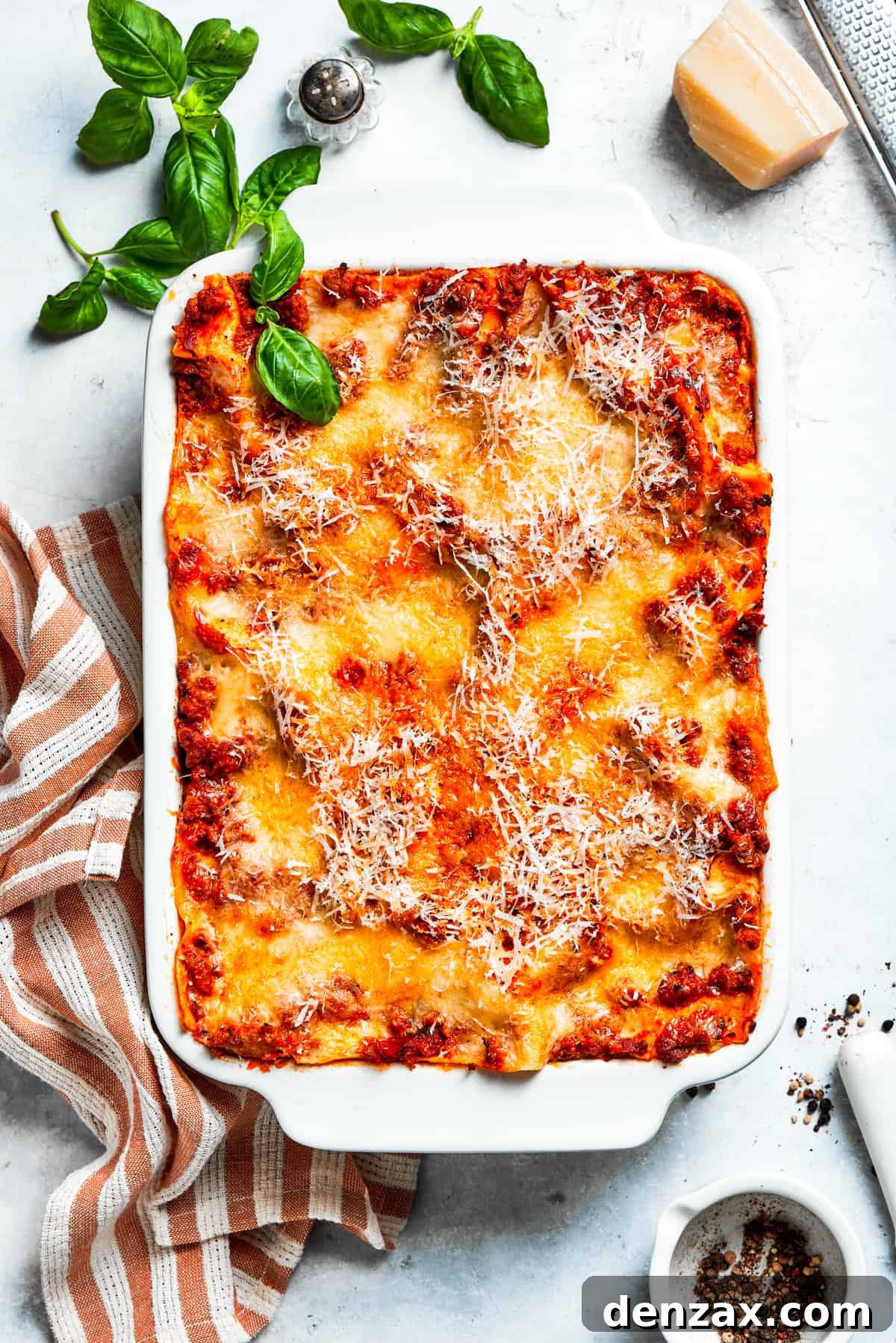 An overhead shot of a freshly baked beef lasagna in a white baking dish, golden and bubbly.