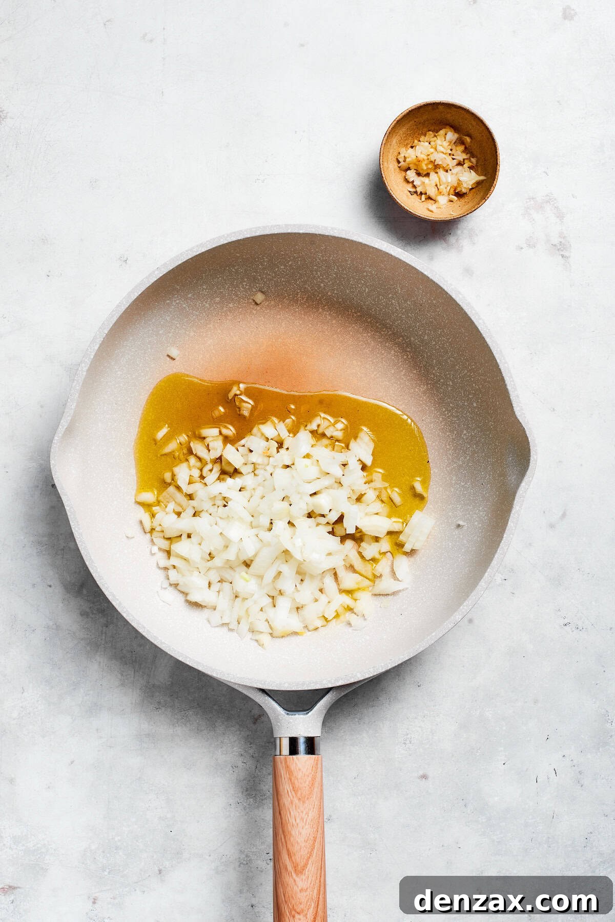 Diced yellow onion and minced garlic sizzling in olive oil in a skillet.