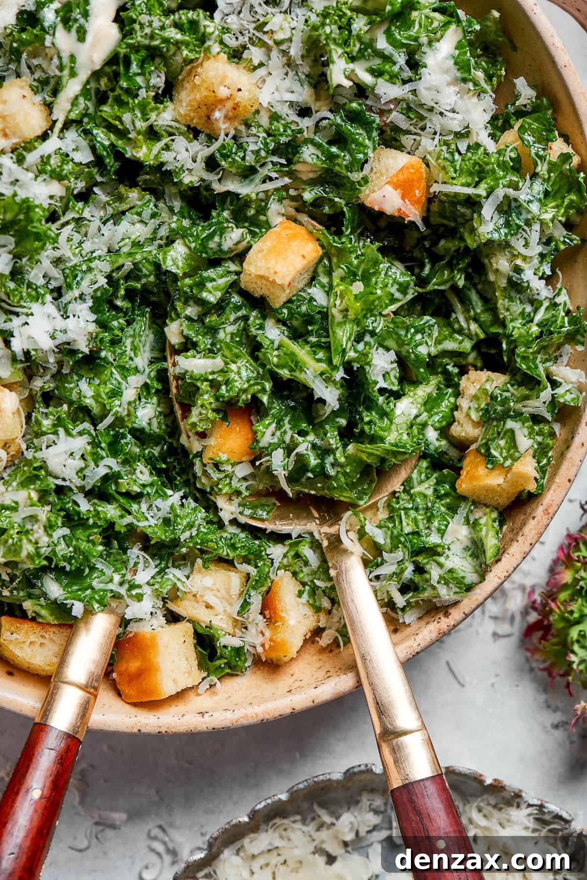 A vibrant green kale salad generously topped with golden brown homemade croutons, ready to be dressed.