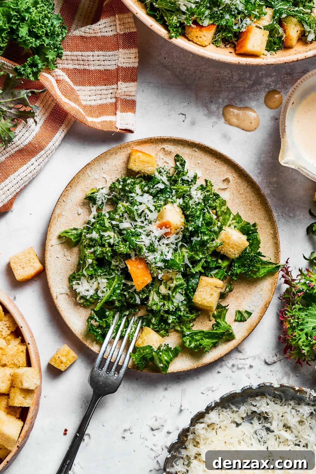 A beautifully arranged plate of kale Caesar salad, generously topped with homemade croutons and grated cheese, ready to be enjoyed.