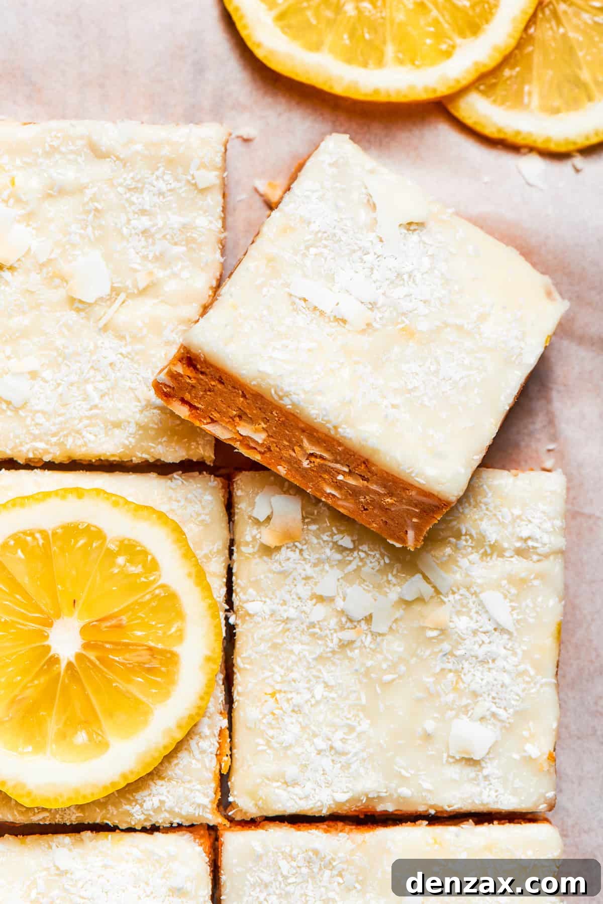 A perfectly portioned square of lemon slice resting atop other golden lemon slices, adorned with a creamy white frosting and a sprinkle of coconut. The vibrant yellow hues evoke a sense of freshness and zest.