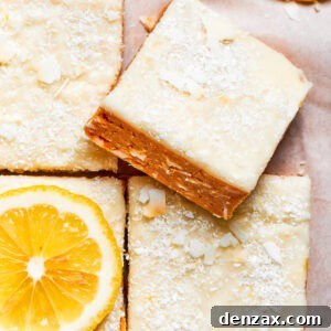 A square of lemon slice on top of other lemon slices, displaying a golden base and creamy white frosting, hinting at its zesty flavor.