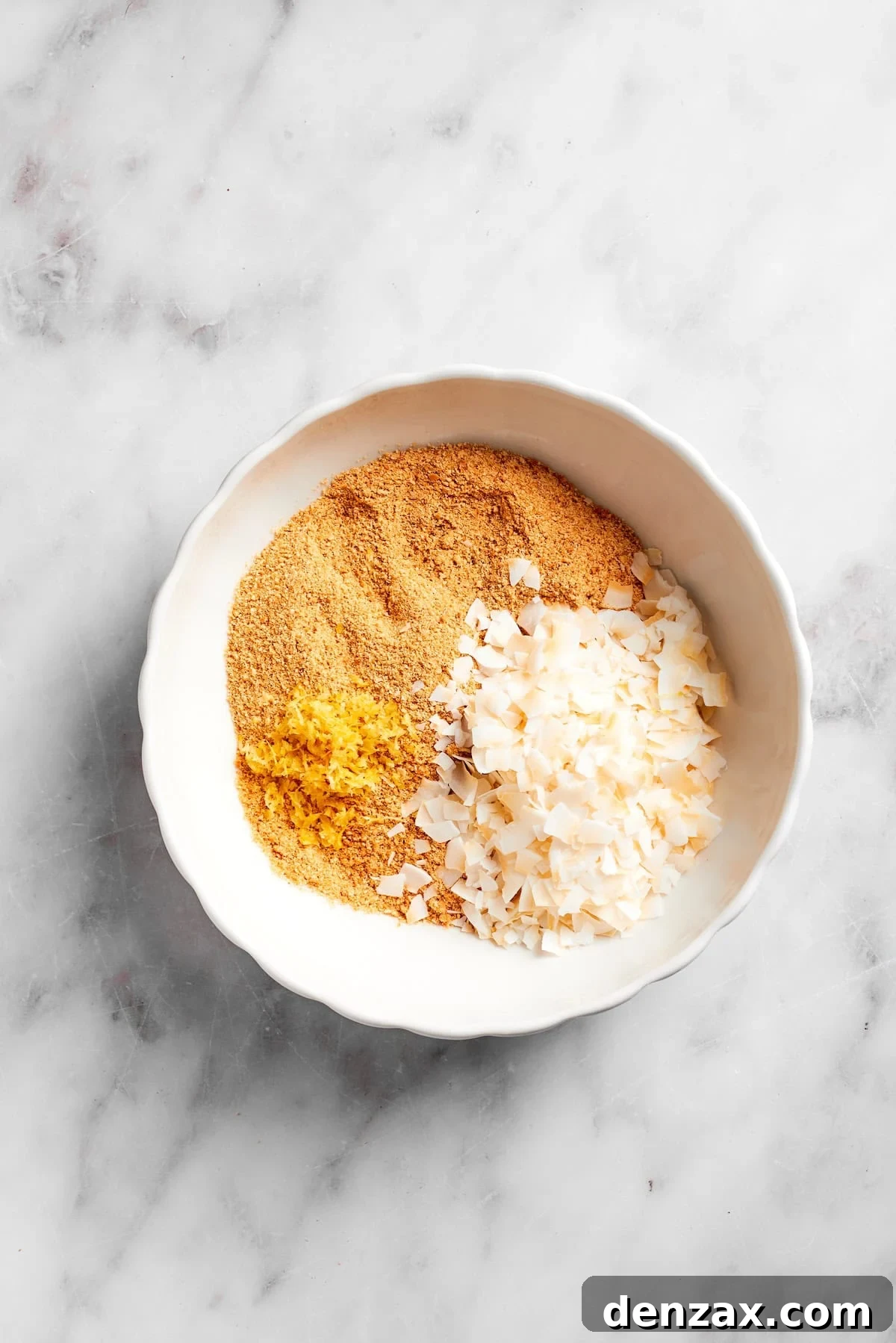 Sweetened flaked coconut being added to a bowl of finely crushed graham crackers, preparing the base for the lemon slice.