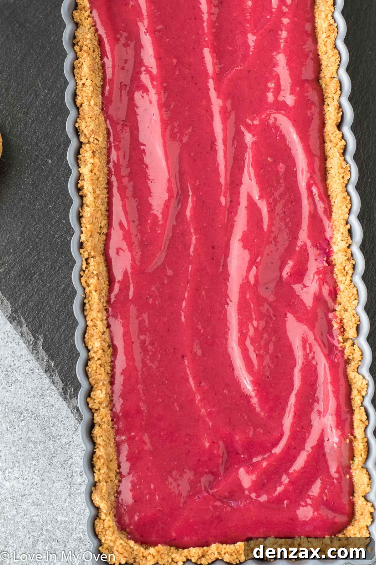 Smooth, glossy cranberry curd poured into a golden gingersnap tart crust, chilling in the refrigerator.