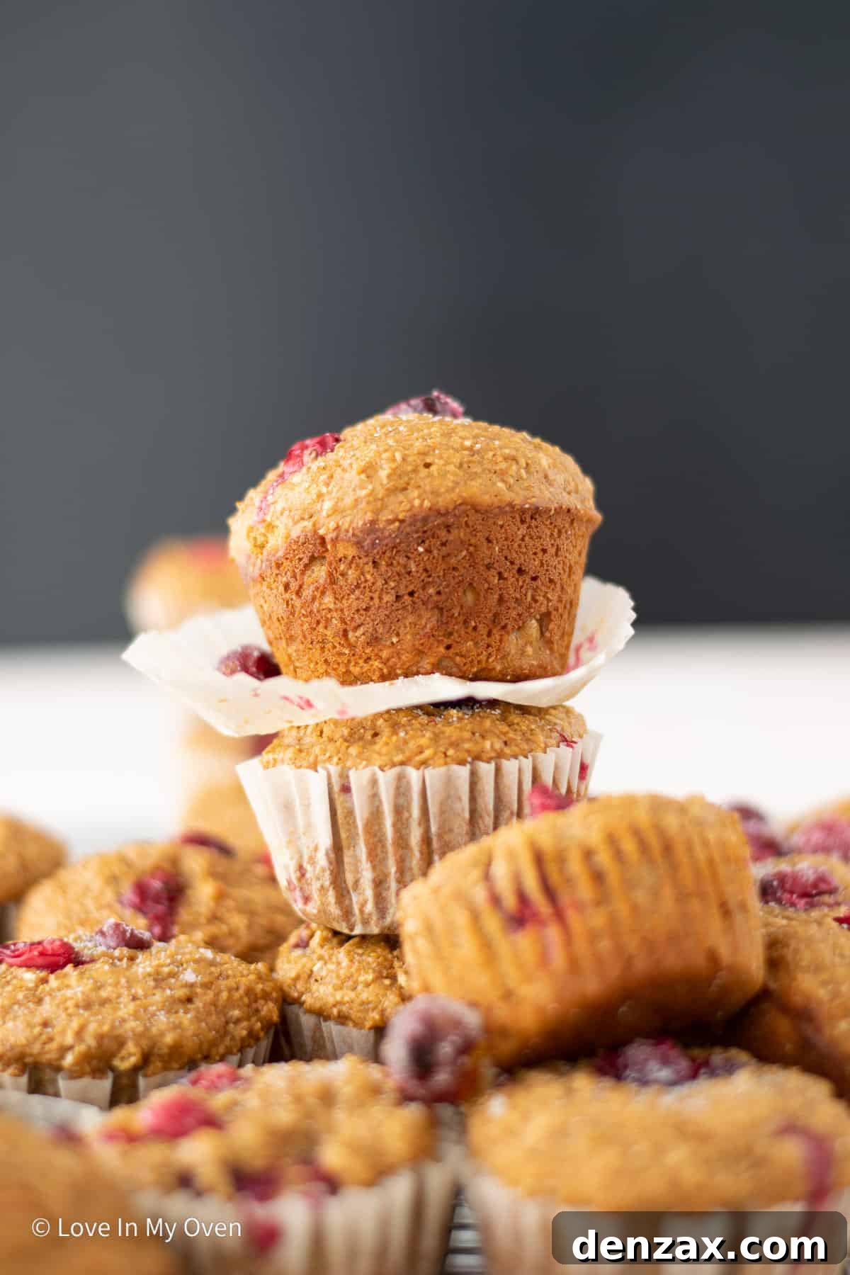 A basket full of golden-brown cranberry bran muffins, garnished with fresh cranberries.