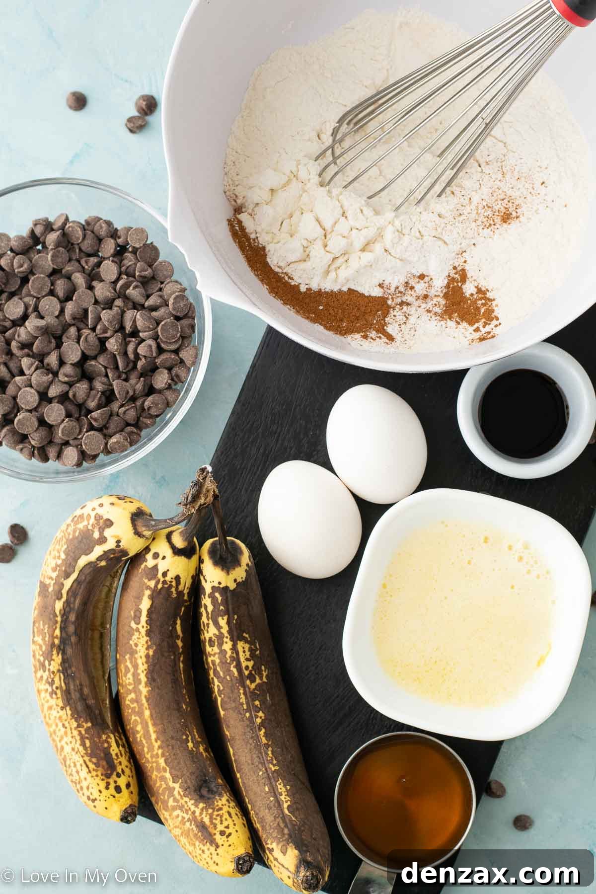 Bowl of mashed ripe bananas next to a mixing bowl with dry ingredients and another with wet ingredients, ready for making banana chocolate chip muffins.