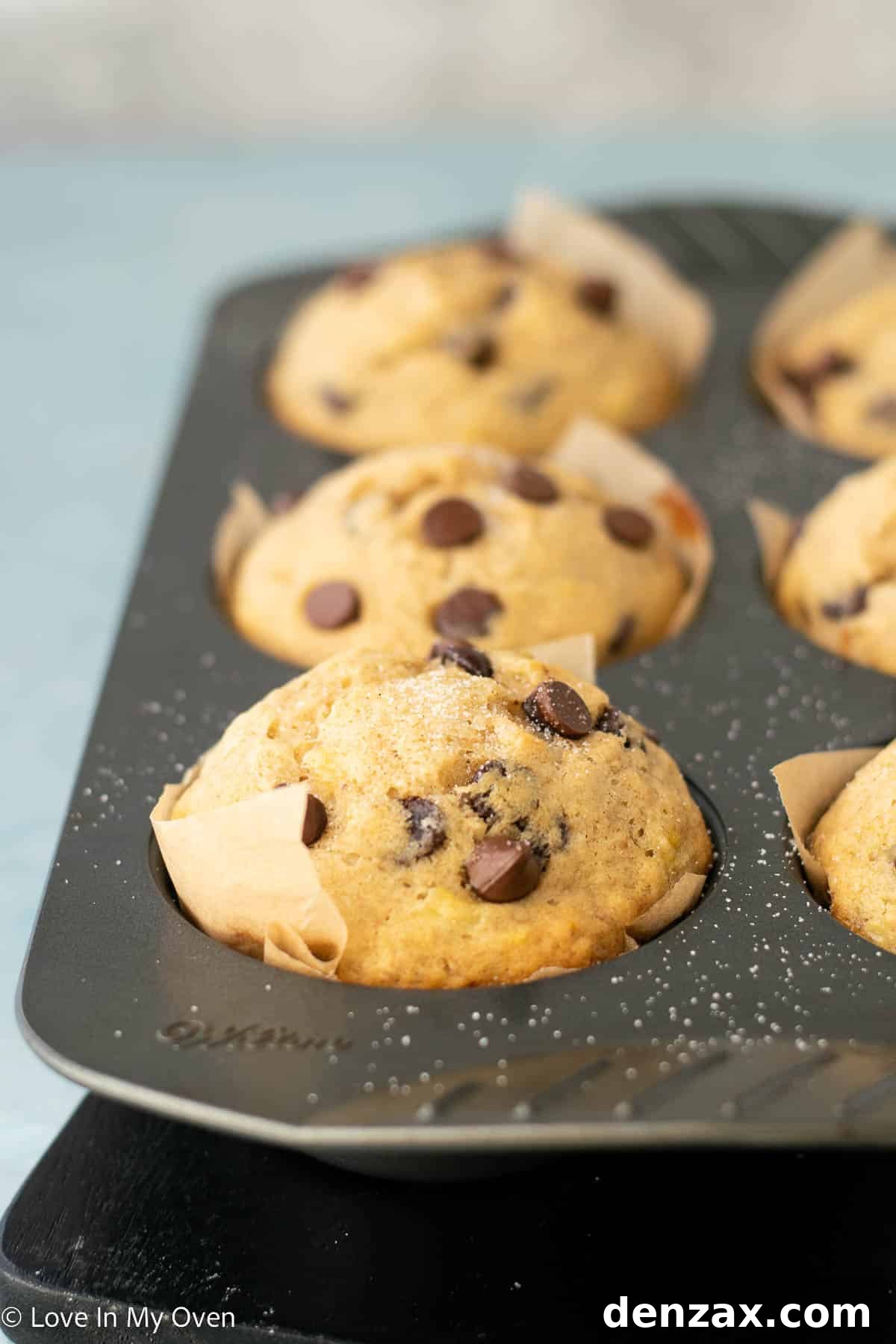 Close-up of a perfectly baked jumbo banana chocolate chip muffin on a cooling rack, showing its golden-brown top and moist interior.