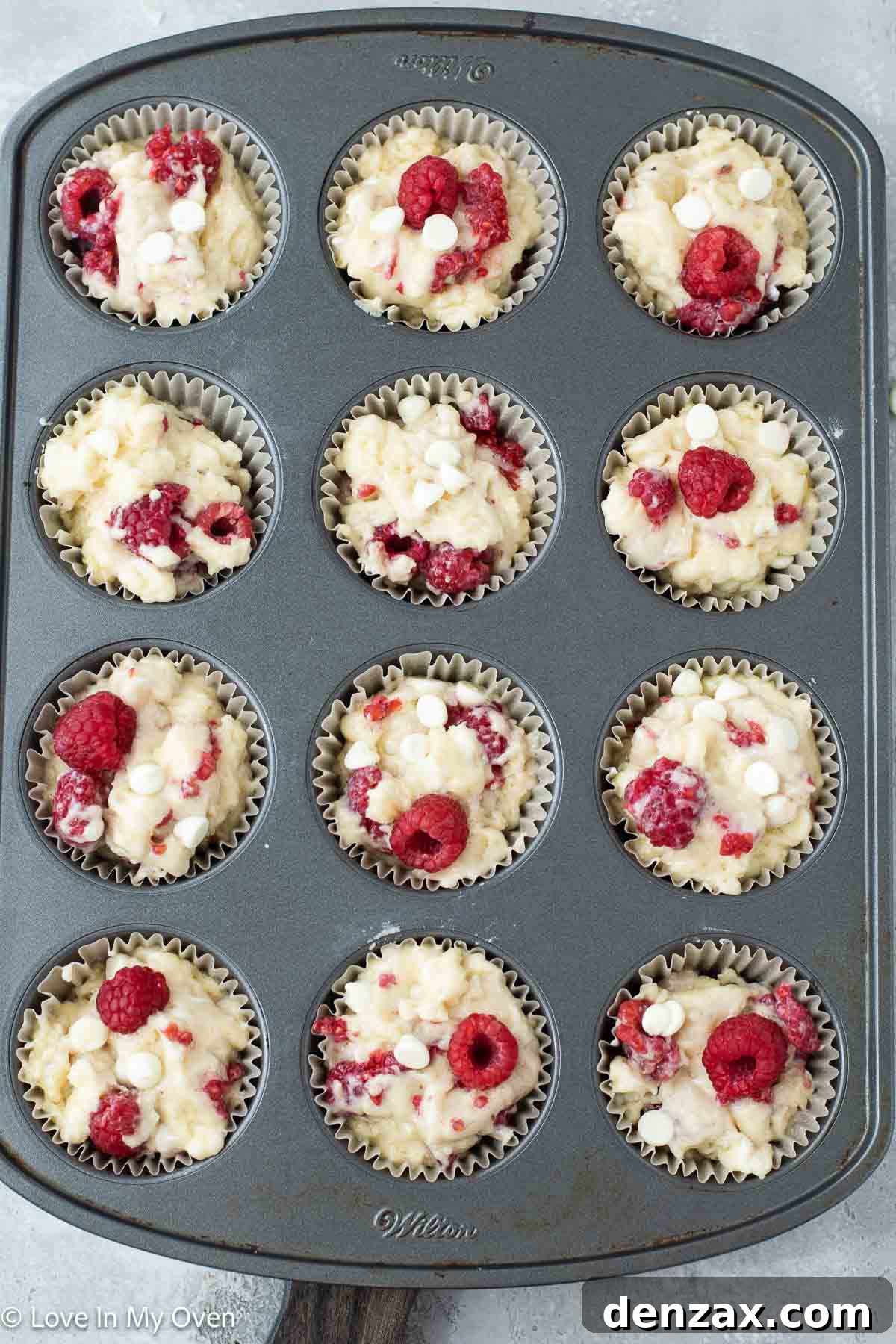 Sweet Raspberry White Chocolate Delights 5 Muffin batter scooped into a muffin tin.