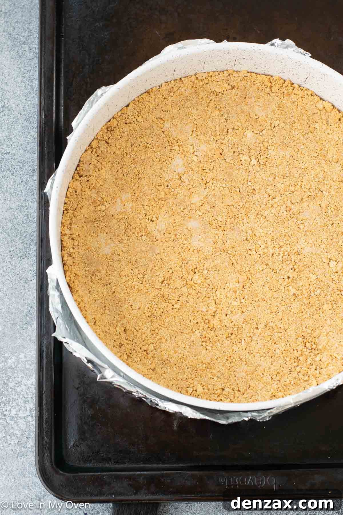 Graham cracker crust being pressed into a springform pan