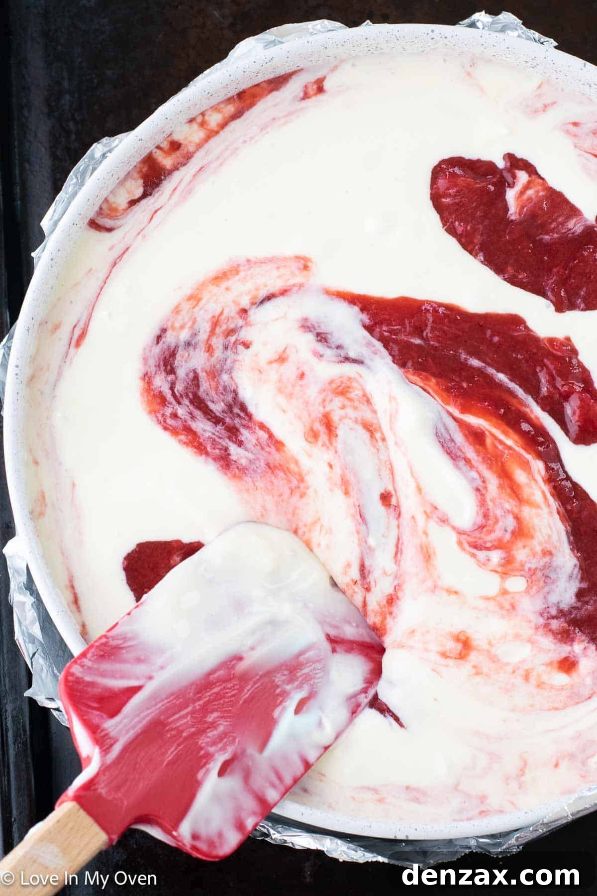 Strawberry rhubarb compote being swirled into cheesecake batter