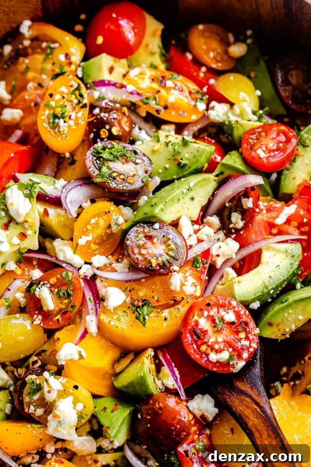 close up top shot of a salad with cherry tomatoes, heirloom tomatoes, avocado, and crumbled bleu cheese
