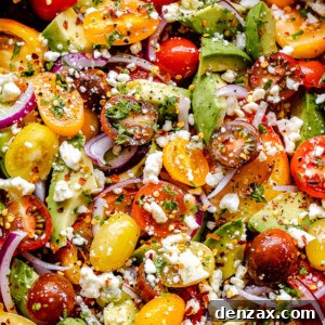 top shot of a wooden salad bowl filled with tomatoes, onions, avocado, and bleu cheese