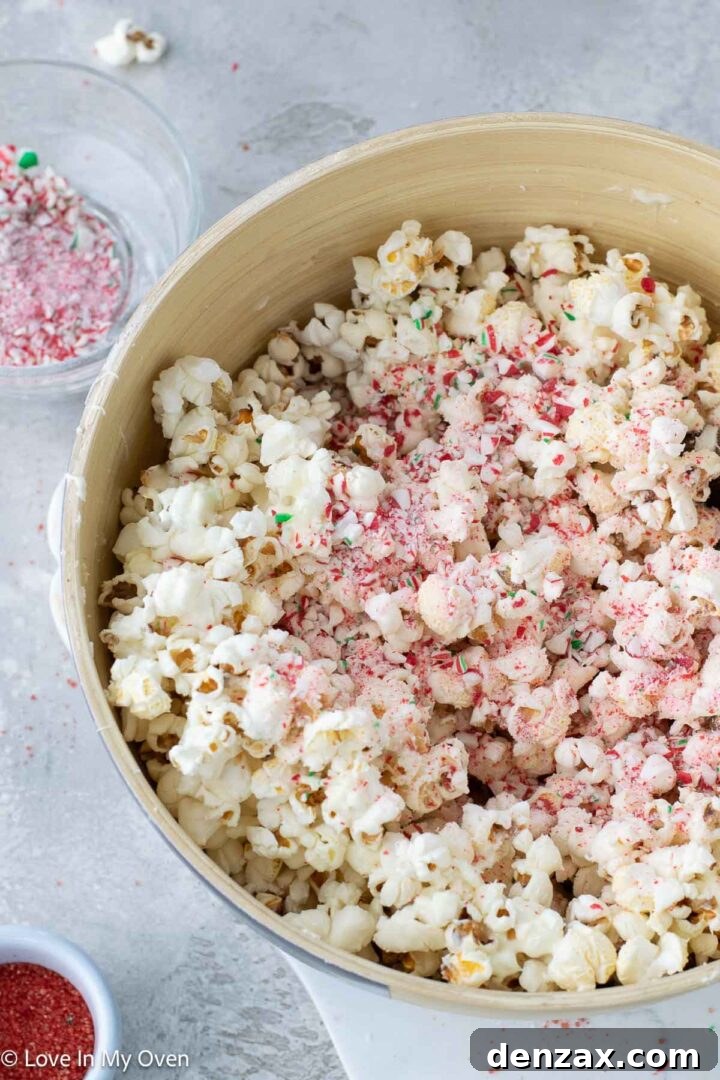 Spreading peppermint white chocolate popcorn on a baking sheet.
