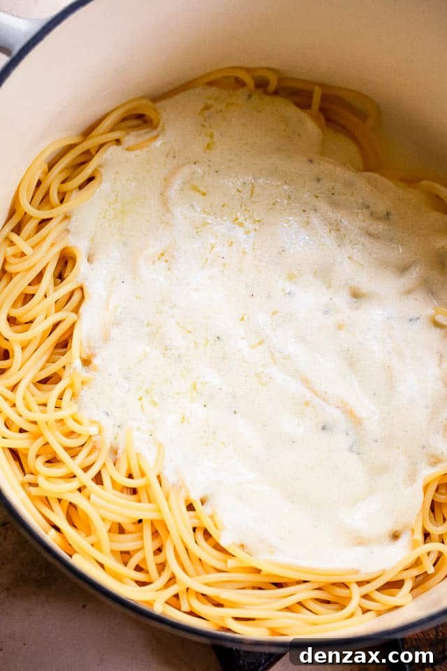 This quick Cream Cheese Spaghetti offers a comforting, cheesy, and creamy pasta dinner that's downright delicious! white dutch oven with spaghetti and white cream sauce on top