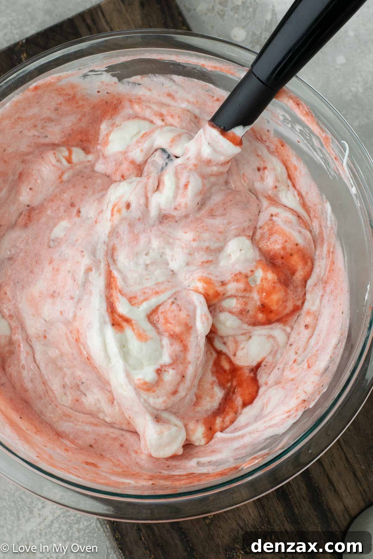 Strawberry puree being folded into the meringue and whipped cream mixture