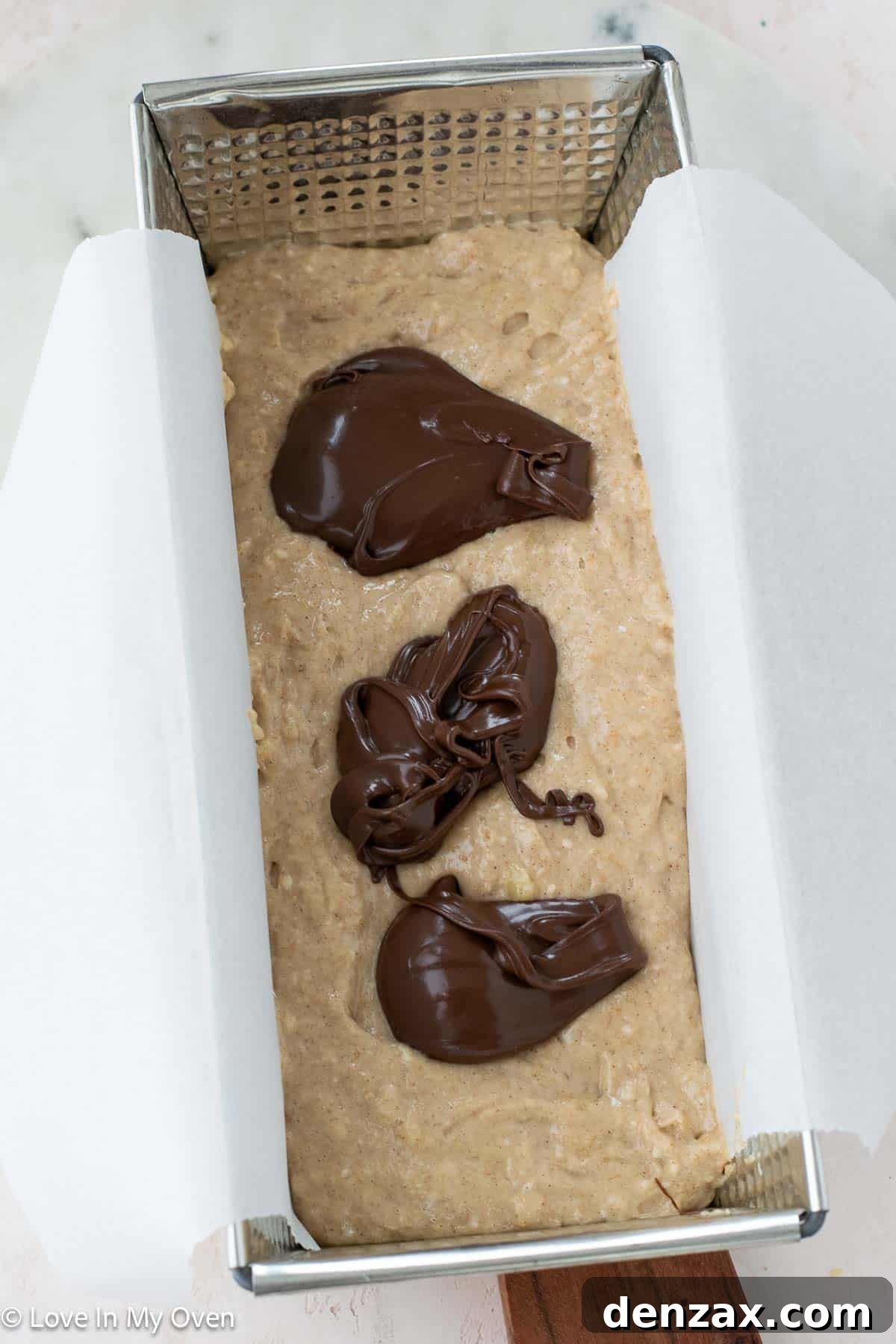 Nutella Banana Bread being lifted out of the pan using parchment paper