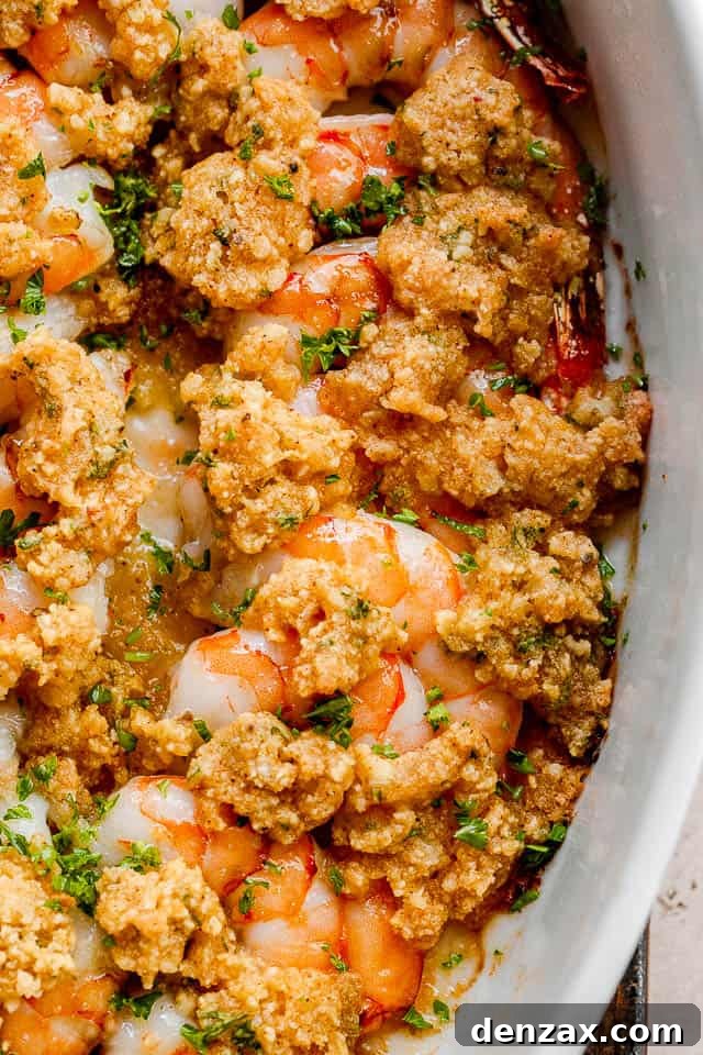 A tantalizing close-up shot of the baked garlic butter shrimp, showcasing the crispy golden breadcrumb topping and the juicy, perfectly cooked shrimp within the white baking dish. The edges are slightly browned, indicating a perfect bake.