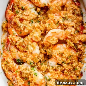 overhead shot of arranged shrimp in a white oval dish and topped with garlic butter and breadcrumbs mixture
