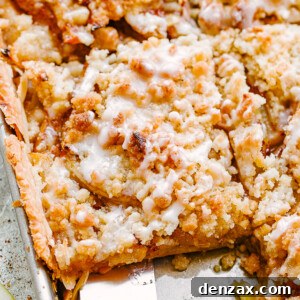 A spatula removes a slice of Dutch apple slab pie from a sheet pan, ready to be served.