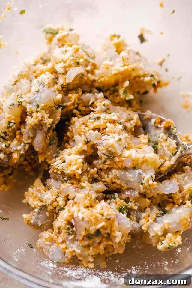 Close-up of the raw mixture for coconut shrimp cakes in a mixing bowl before shaping.
