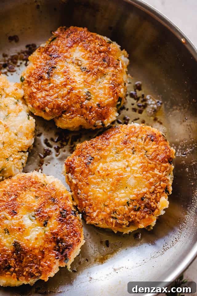 Coconut shrimp cakes sizzling in a large skillet filled with hot oil, cooking to a golden perfection.