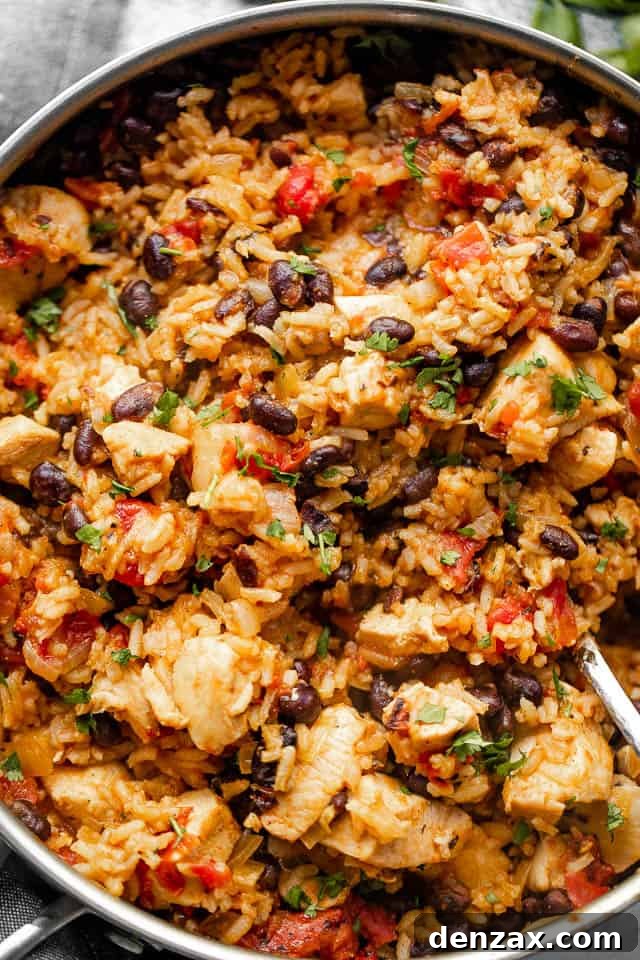 Mixing through rice and chicken in a skillet before adding cheese.