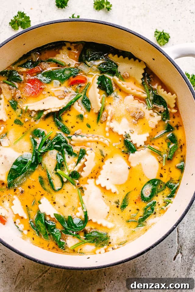 Overhead image of a vibrant, creamy ravioli soup in a large soup pot, brimming with ravioli, ground turkey, and fresh spinach.