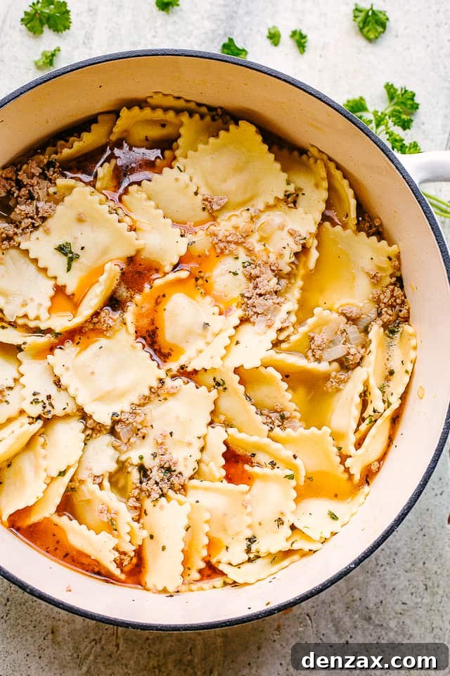 A large pot on the stove with sautéed onions, carrots, and browned ground turkey, forming the aromatic base for the ravioli soup.