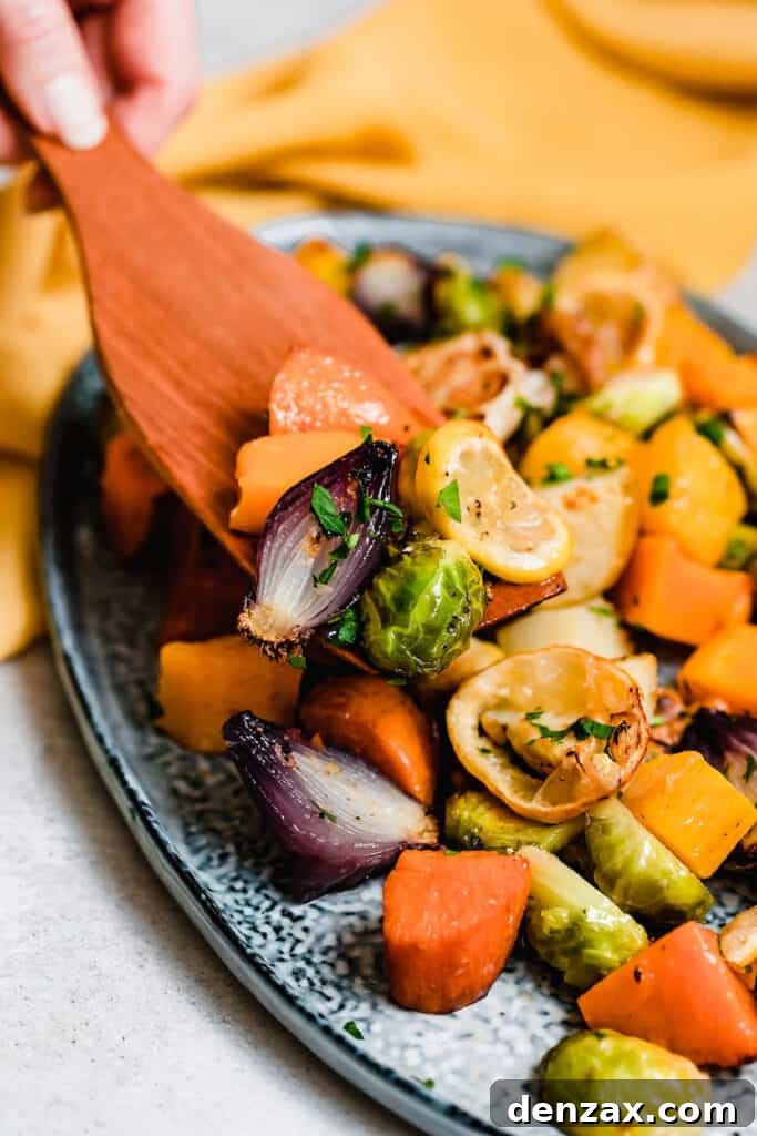 A wooden spoon scooping roasted vegetables off a blue platter.