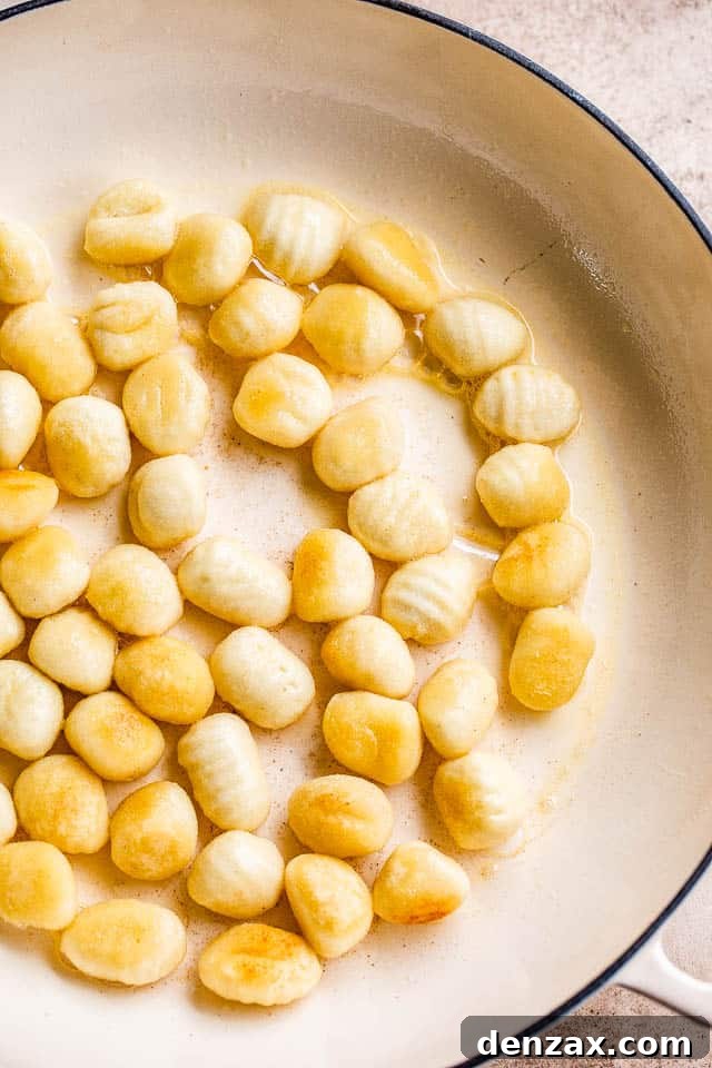 frying gnocchi in a white skillet, showing a golden brown crust