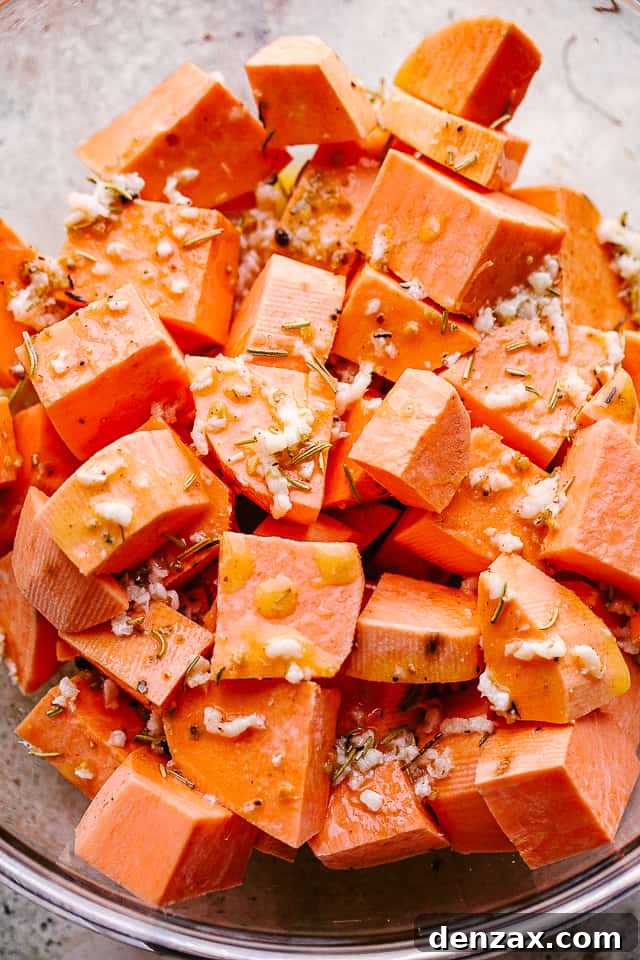 Overhead shot of chopped raw sweet potatoes in a large mixing bowl before seasoning.