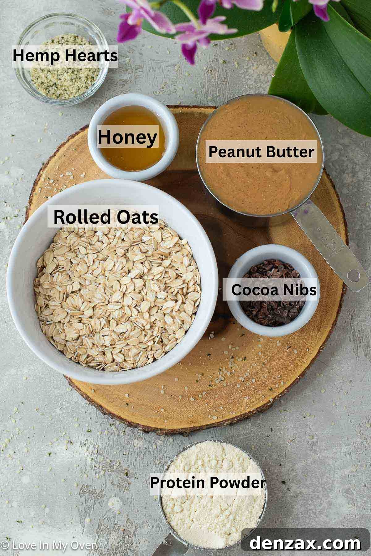 Ingredients for healthy no-bake peanut butter protein balls laid out on a white surface with measuring cups and spoons.