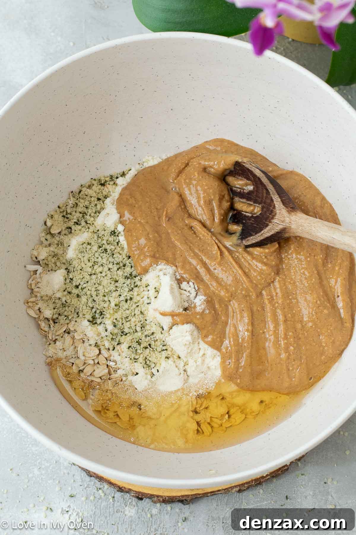 Mixing ingredients for peanut butter protein balls in a large bowl with a wooden spoon.
