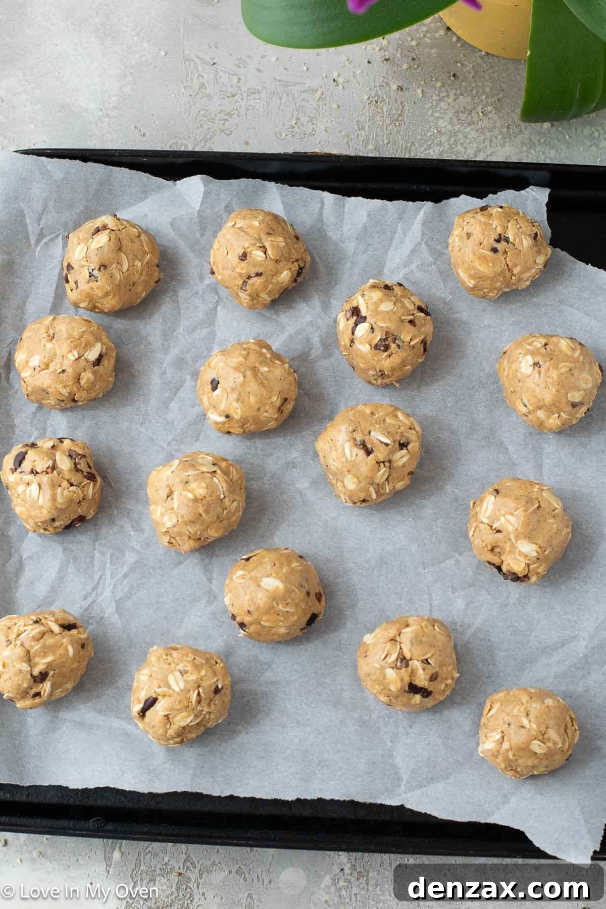 Peanut butter protein balls neatly arranged on a parchment-lined baking sheet, ready for chilling.
