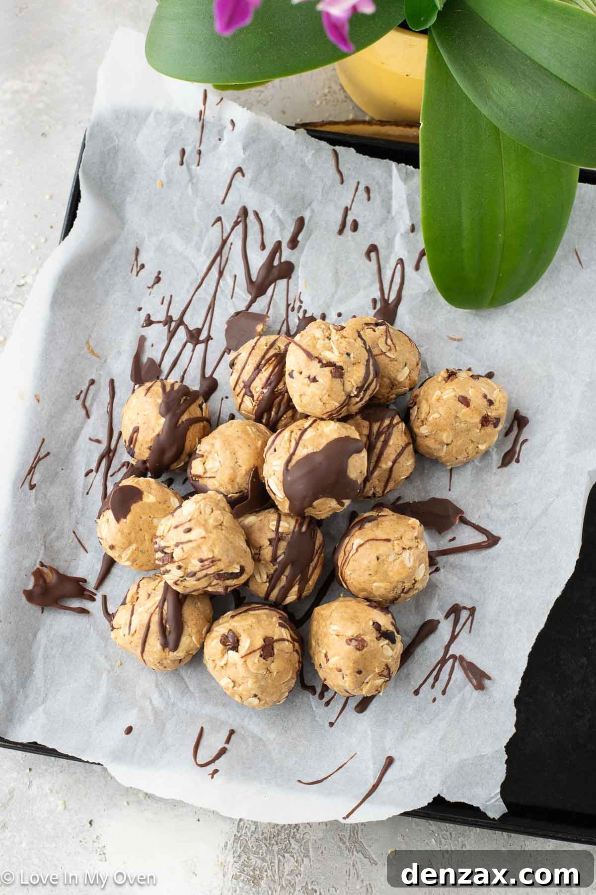 Close-up of three finished peanut butter protein balls with chocolate drizzle, on a white surface.