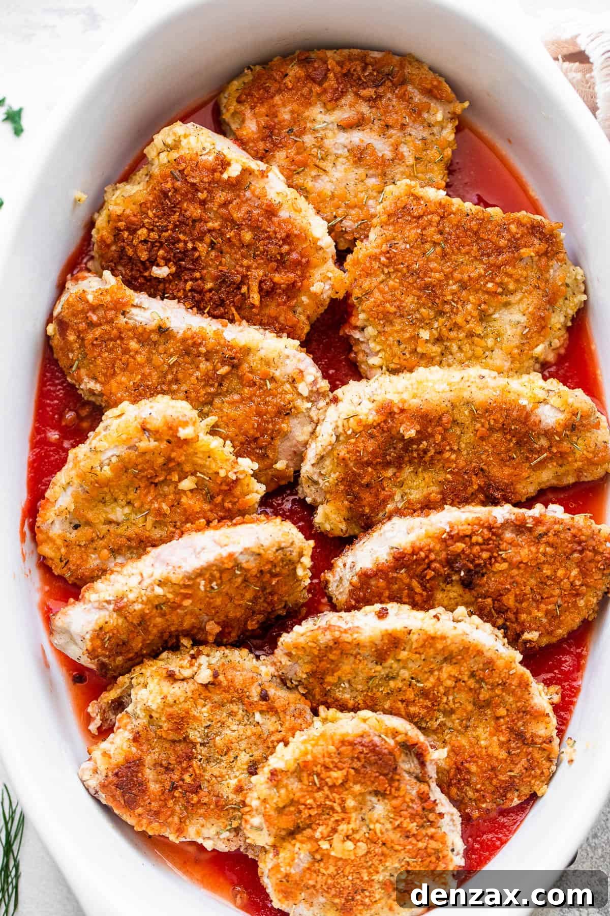Breaded pork medallions perfectly arranged in a white ceramic baking dish, ready for sauce and cheese.