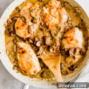 Chicken in a creamy marsala sauce with a wooden serving spoon.
