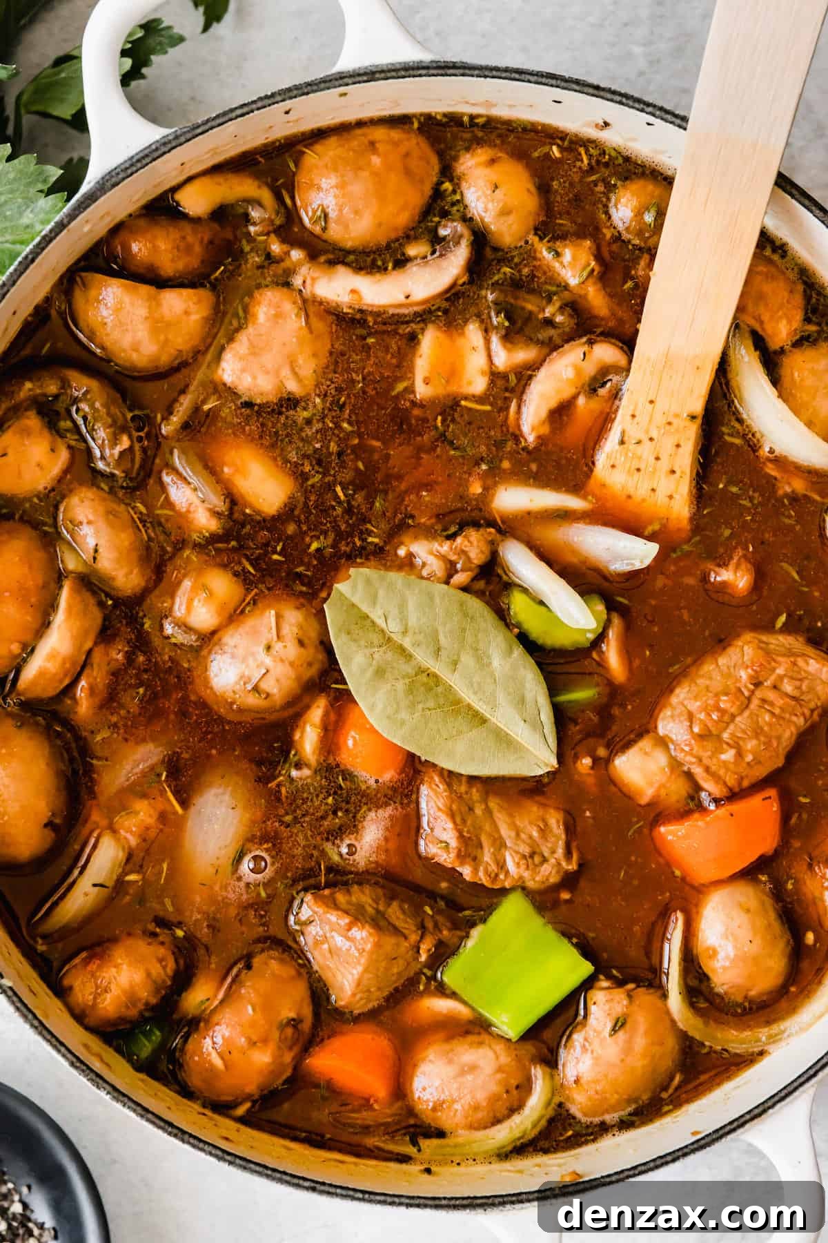 A large pot of rich beef stew simmering, with a fresh bay leaf nestled on top, signifying the aromatic depth of the dish.