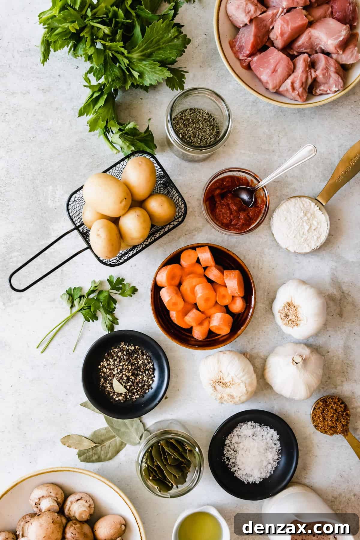 A collection of fresh ingredients laid out, including beef, various vegetables, and a bottle of Guinness, prepared for making Irish beef stew.