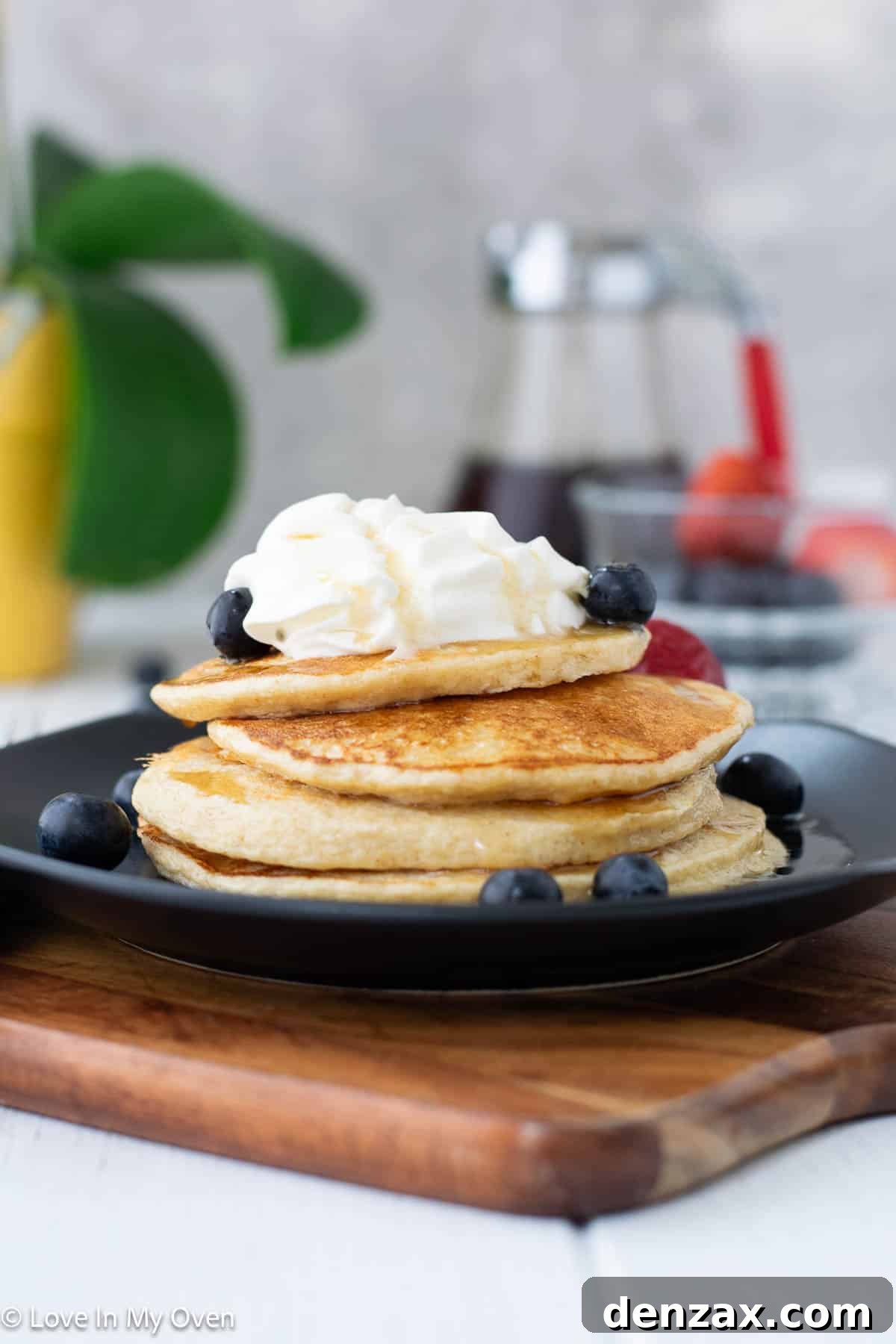 Fluffy stack of high protein cottage cheese pancakes with fresh berries and maple syrup drizzle, photographed from above.
