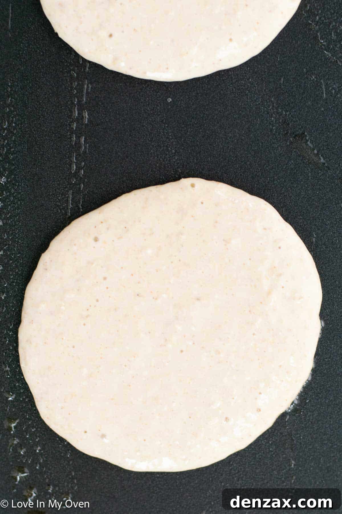 A hand drizzling maple syrup over a stack of protein pancakes.